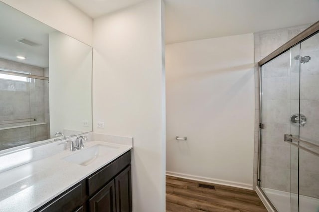 bathroom with hardwood / wood-style floors, vanity, and an enclosed shower