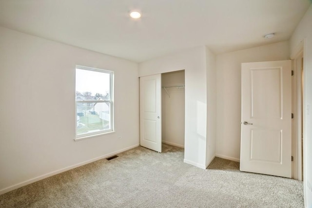 unfurnished bedroom with light carpet and a closet