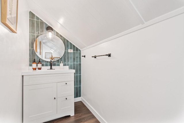 bathroom featuring wood-type flooring, vanity, tile walls, and lofted ceiling