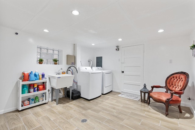 laundry area featuring sink, washing machine and dryer, light hardwood / wood-style floors, and electric panel