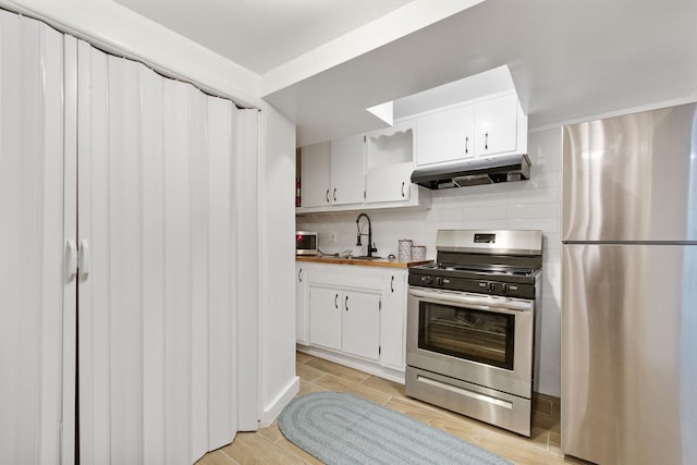 kitchen with decorative backsplash, white cabinetry, appliances with stainless steel finishes, and light hardwood / wood-style flooring