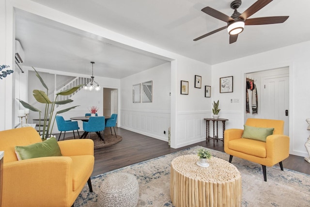 living room with a wall mounted AC, ceiling fan with notable chandelier, and hardwood / wood-style flooring