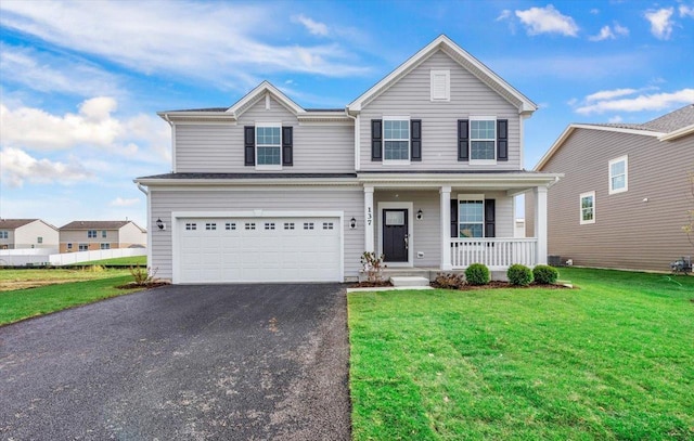 view of front of house featuring covered porch, a garage, and a front lawn