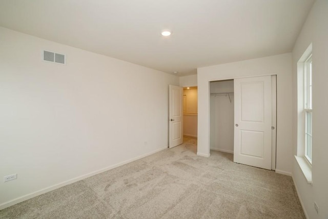 unfurnished bedroom featuring multiple windows, light carpet, and a closet