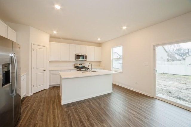 kitchen featuring appliances with stainless steel finishes, dark wood-type flooring, sink, a center island with sink, and white cabinetry