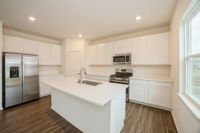 kitchen with an island with sink, stainless steel appliances, white cabinetry, and sink