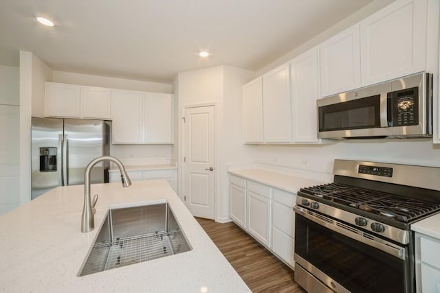 kitchen with white cabinetry, sink, light stone countertops, and appliances with stainless steel finishes