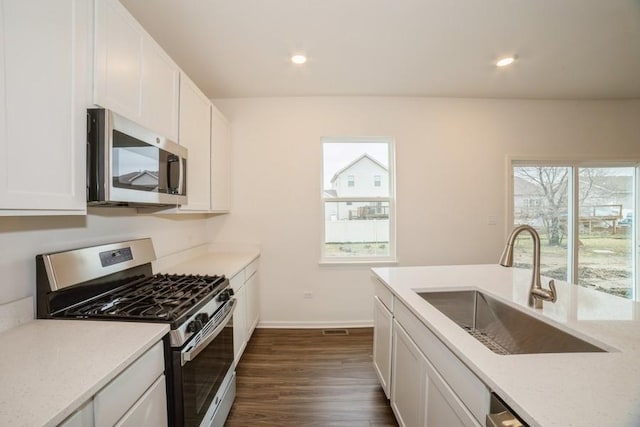 kitchen with light stone counters, white cabinetry, sink, and appliances with stainless steel finishes