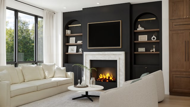 living room with built in features, a premium fireplace, and hardwood / wood-style flooring