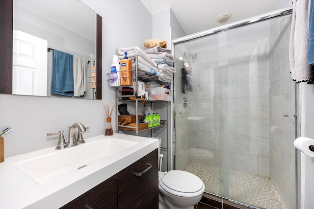 bathroom with tile patterned floors, vanity, a shower with shower door, and toilet