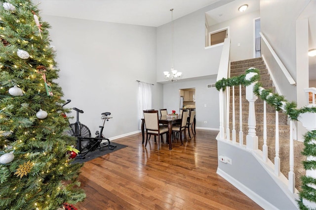 dining room with hardwood / wood-style floors, a high ceiling, and a notable chandelier