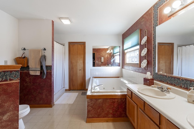 bathroom with vanity, toilet, and tiled bath