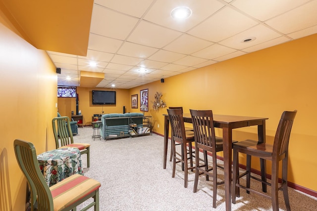 carpeted dining area featuring a paneled ceiling