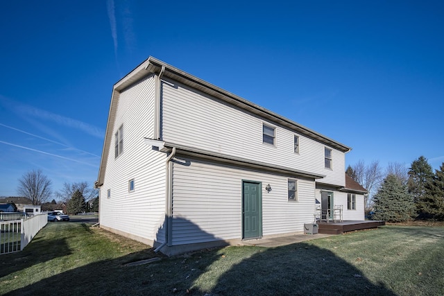 rear view of property featuring a wooden deck and a lawn