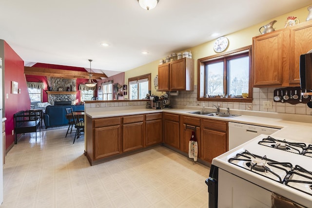 kitchen with tasteful backsplash, a stone fireplace, kitchen peninsula, white appliances, and decorative light fixtures