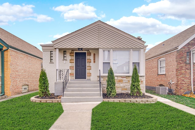 bungalow-style house with central air condition unit and a front lawn