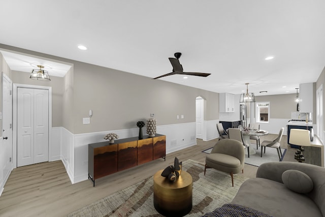 living room featuring light hardwood / wood-style flooring and ceiling fan with notable chandelier