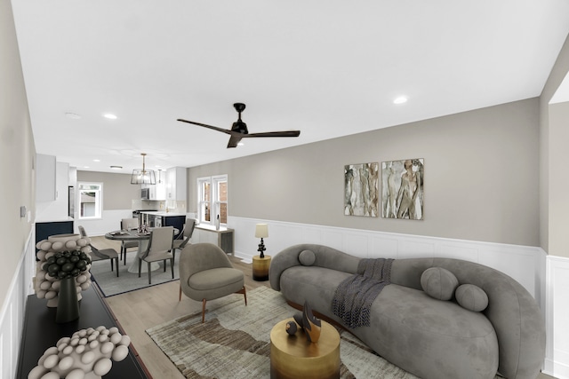 living room with light hardwood / wood-style floors and ceiling fan with notable chandelier