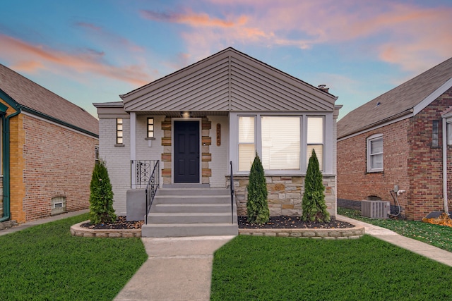 view of front of home featuring a lawn and central air condition unit