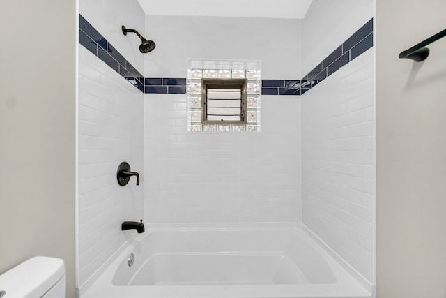 bathroom with tiled shower / bath combo and toilet