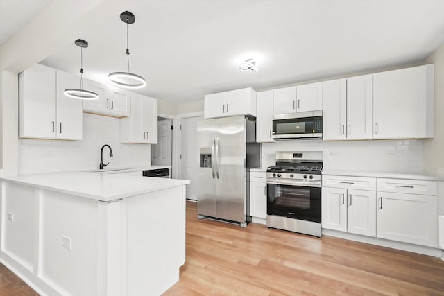 kitchen with appliances with stainless steel finishes, sink, decorative light fixtures, light hardwood / wood-style flooring, and white cabinetry