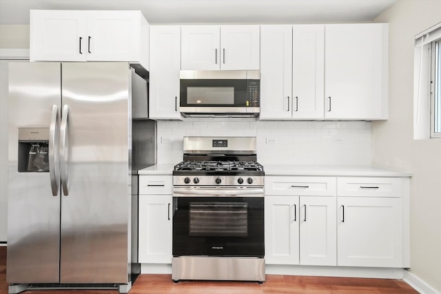 kitchen featuring backsplash, light hardwood / wood-style flooring, white cabinets, and stainless steel appliances