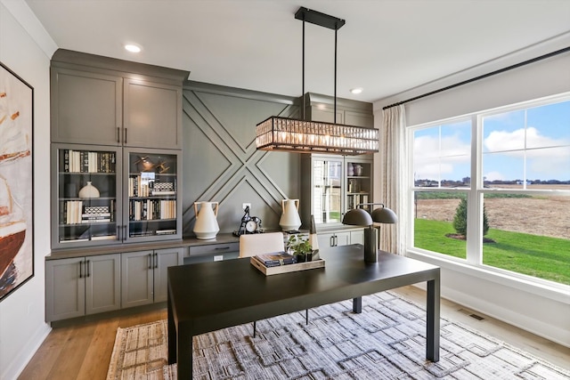 home office with light hardwood / wood-style flooring and a notable chandelier