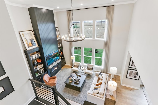 living room featuring a notable chandelier, crown molding, and light hardwood / wood-style flooring