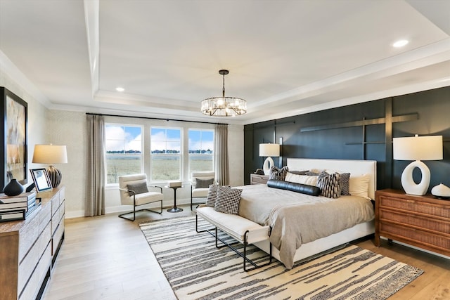 bedroom featuring a raised ceiling, light wood-type flooring, and an inviting chandelier