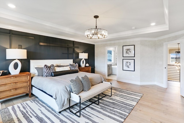 bedroom featuring hardwood / wood-style floors, ensuite bathroom, a raised ceiling, and a chandelier