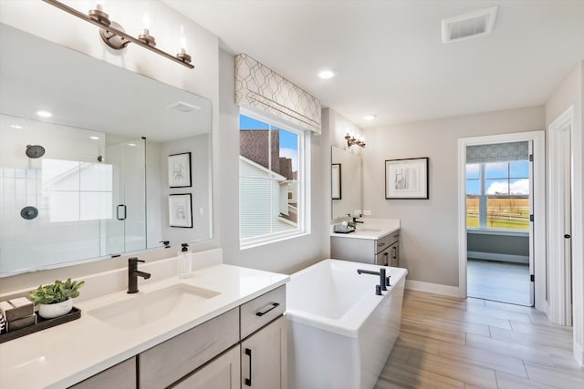 bathroom with plus walk in shower, hardwood / wood-style floors, and vanity