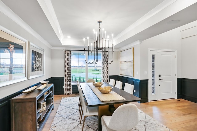 dining space featuring a tray ceiling, a wealth of natural light, light hardwood / wood-style flooring, and a notable chandelier