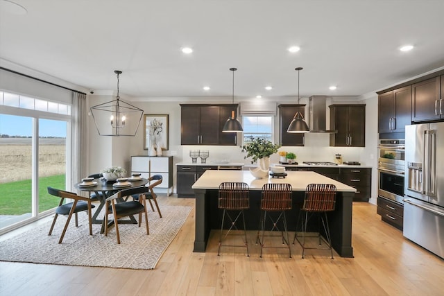 kitchen with pendant lighting, light hardwood / wood-style flooring, appliances with stainless steel finishes, a kitchen island, and extractor fan