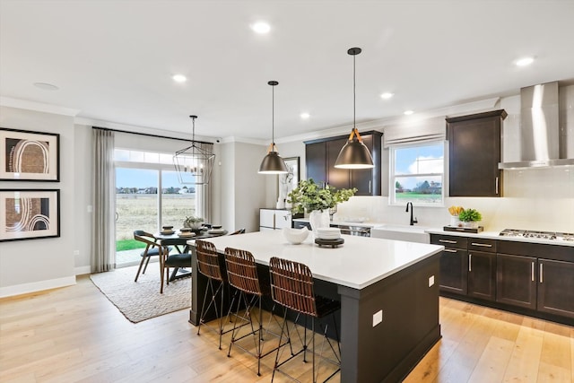 kitchen featuring pendant lighting, a kitchen island, a wealth of natural light, and wall chimney range hood