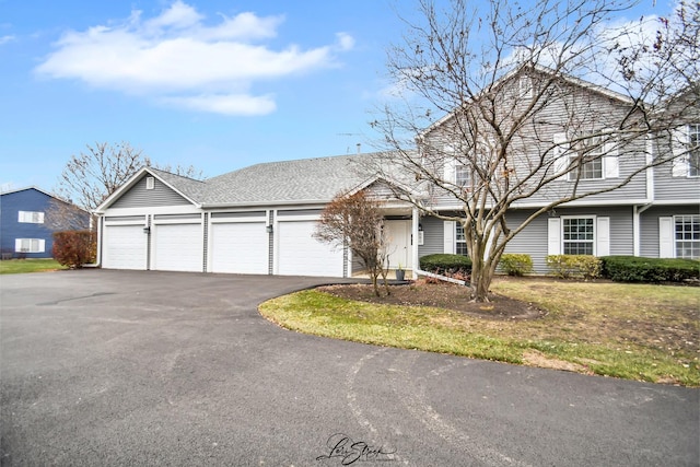 view of front of property with an attached garage, a shingled roof, and aphalt driveway