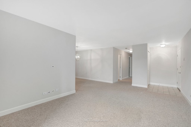 interior space with a chandelier, light colored carpet, and baseboards