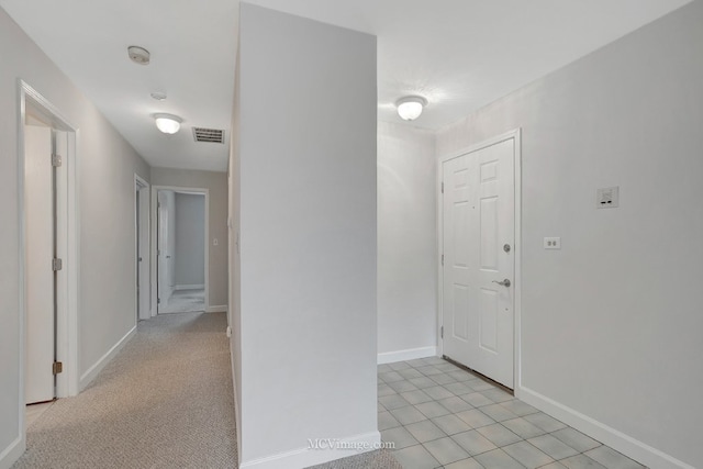 hall featuring light carpet, visible vents, and baseboards