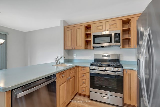 kitchen with a peninsula, stainless steel appliances, light countertops, open shelves, and a sink