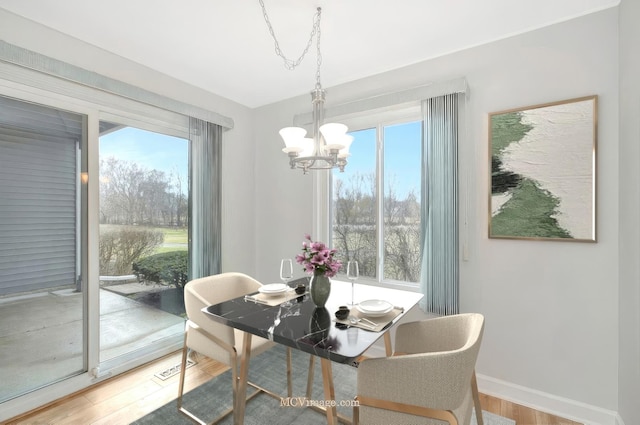 dining room featuring a chandelier, baseboards, and wood finished floors