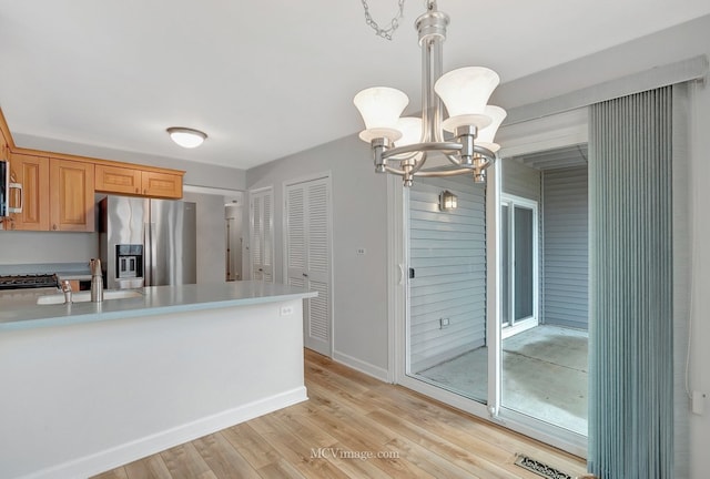 kitchen featuring light wood finished floors, stainless steel appliances, a sink, and light countertops