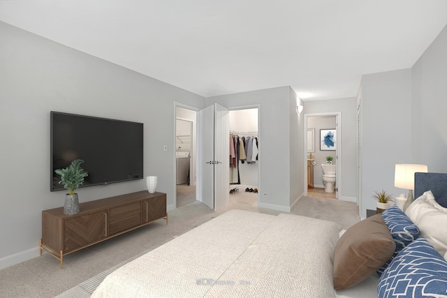 bedroom featuring light carpet, a spacious closet, washer / clothes dryer, and baseboards