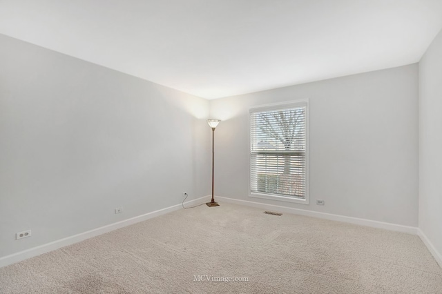 unfurnished room featuring visible vents, light carpet, and baseboards