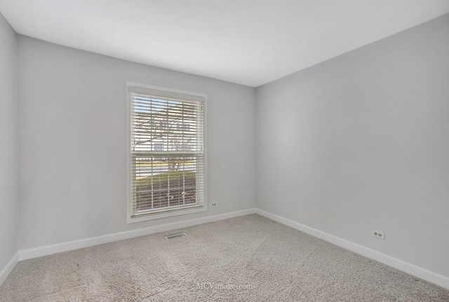 empty room with carpet, visible vents, and baseboards