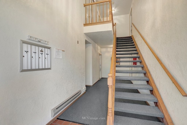 stairs featuring a textured wall, a baseboard radiator, and mail area