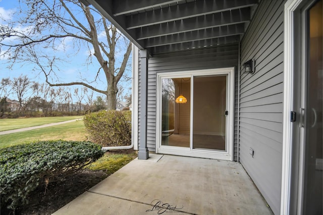 entrance to property featuring a patio and a lawn