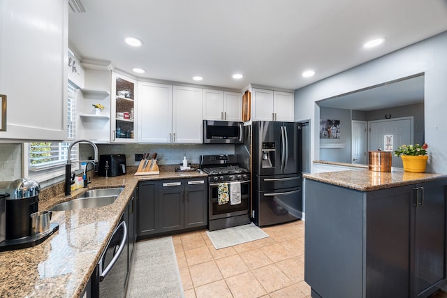 kitchen featuring sink, stainless steel appliances, tasteful backsplash, light stone counters, and white cabinets