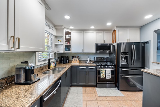 kitchen featuring white cabinets, appliances with stainless steel finishes, light stone counters, and sink