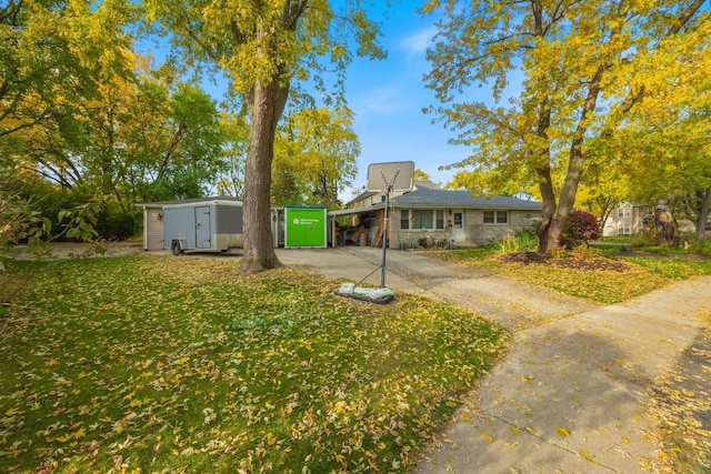 view of front facade featuring a front lawn and a storage shed