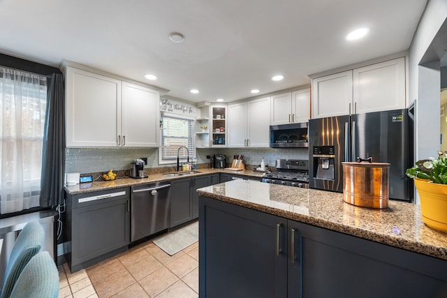 kitchen with sink, tasteful backsplash, light stone counters, white cabinets, and appliances with stainless steel finishes