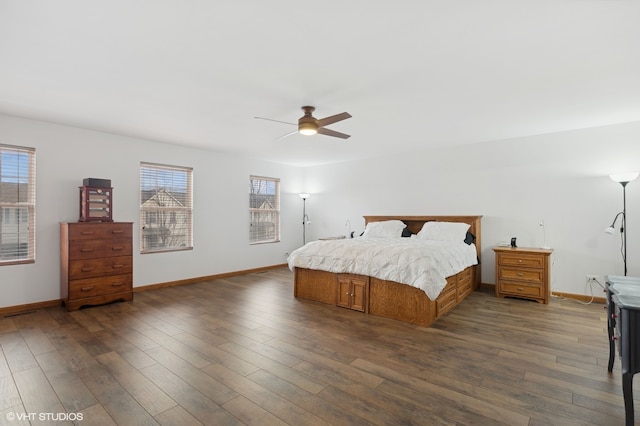 bedroom with ceiling fan, dark wood-type flooring, and multiple windows